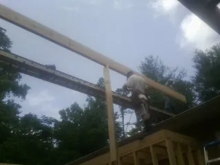 Carpenter setting a ridge beam over a new addition frame — Ice Dam Removal by Roofing Brothers in Gerton