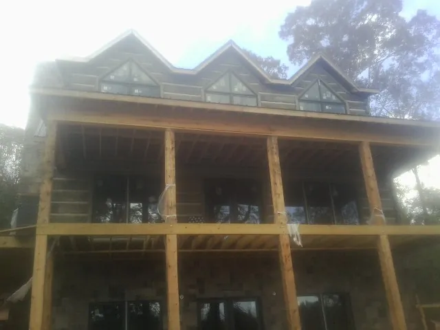 Dormers and porch framing on a large log home under construction — Roof Coating work by our crew in Gerton
