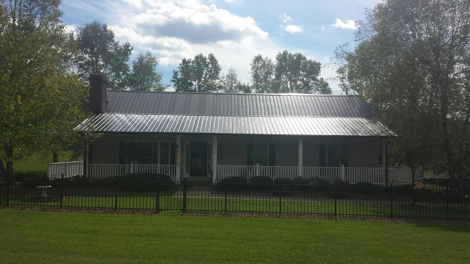 Gray metal roof on a brick ranch with a full width front porch — Gutter Guard Installation work by our crew in Gerton