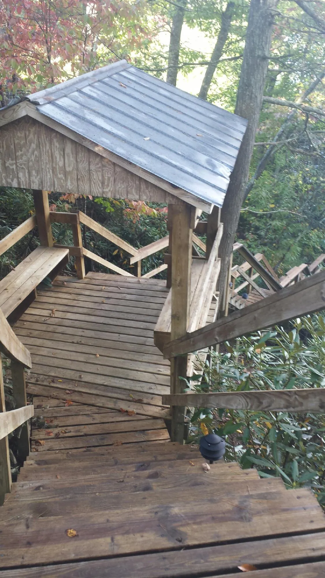Metal roofed shelter over wooden steps on a wooded walkway — Skylight Repair & Installation work by our crew in Gerton