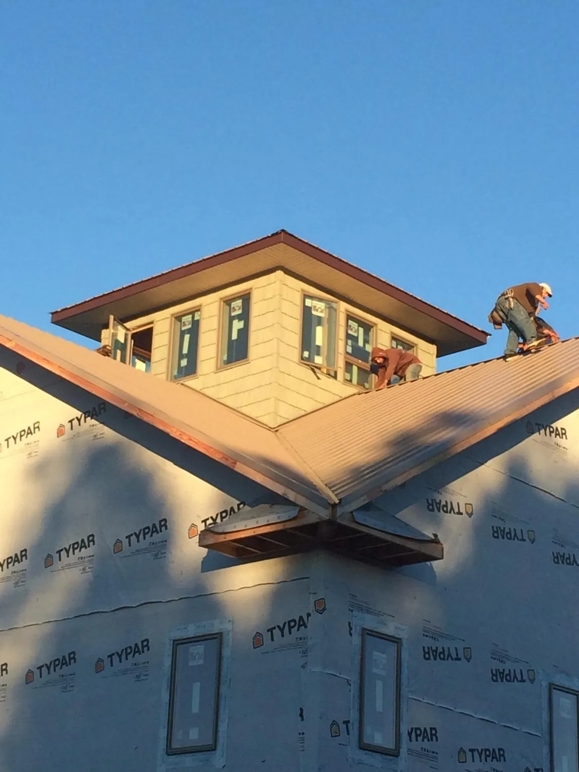 Roofers working around a rooftop cupola on a new metal roof at sunset — Roof Waterproofing in Gerton by Roofing Brothers